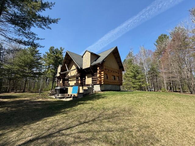 view of home's exterior with a lawn and log exterior