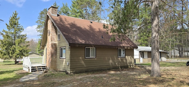 view of property exterior featuring a shingled roof, a chimney, and a deck