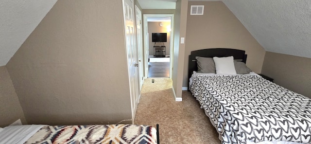 carpeted bedroom with a textured ceiling, visible vents, and vaulted ceiling