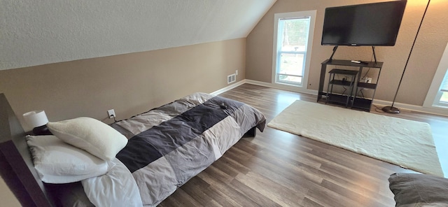 bedroom with visible vents, wood finished floors, vaulted ceiling, and multiple windows
