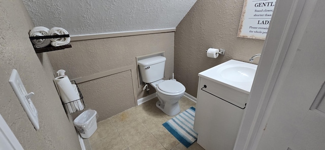 bathroom with vanity, a textured wall, tile patterned flooring, and toilet