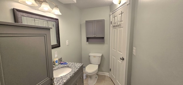 bathroom featuring vanity, toilet, baseboards, a textured ceiling, and tile patterned floors