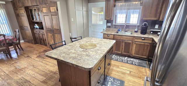kitchen featuring a sink, freestanding refrigerator, a kitchen island, and wood finished floors