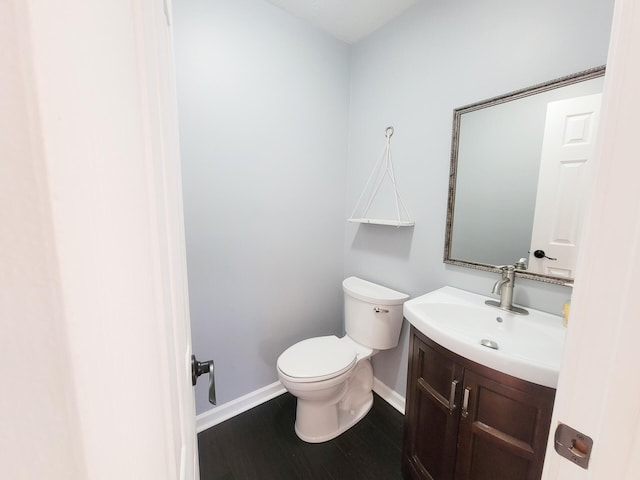 bathroom featuring baseboards, wood finished floors, toilet, and vanity