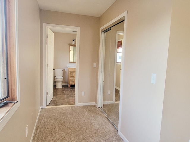 corridor with baseboards and carpet flooring