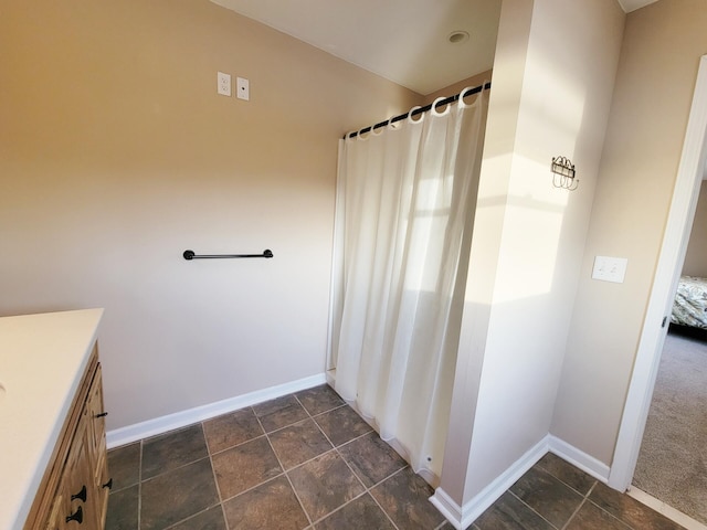 full bathroom with baseboards, stone finish floor, and vanity