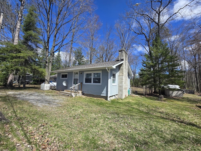 bungalow featuring a chimney, a shingled roof, and a front yard