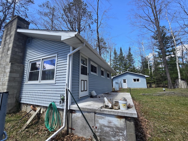 rear view of property with a lawn and an outdoor structure