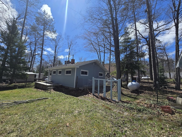 view of property exterior with fence, a yard, and a chimney