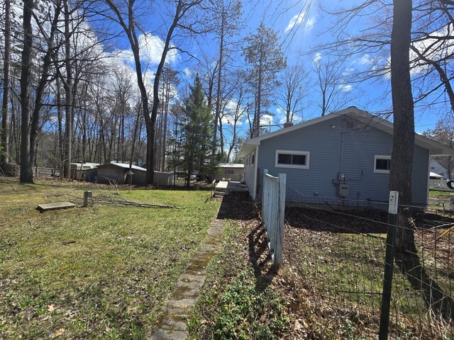 view of side of home with a lawn and fence