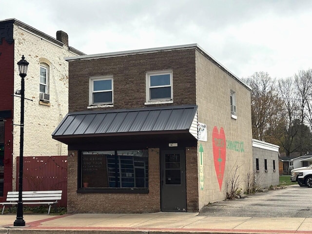view of front of property featuring brick siding, metal roof, and cooling unit