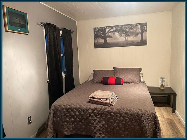 bedroom with ornamental molding and wood finished floors