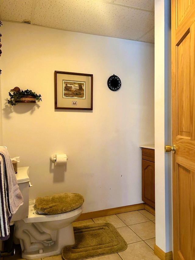 half bathroom featuring baseboards, tile patterned flooring, vanity, and toilet