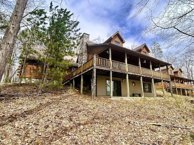 rear view of property featuring a wooden deck and a chimney