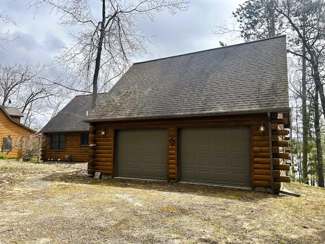 view of front of house with a garage, log siding, and a shingled roof