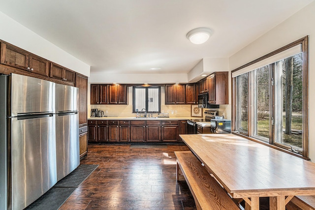 kitchen featuring appliances with stainless steel finishes, dark wood finished floors, dark brown cabinets, a sink, and light countertops