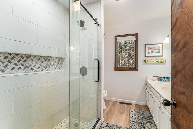 full bath featuring vanity, a stall shower, wood finished floors, and visible vents