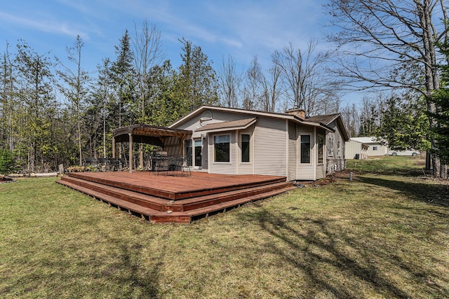 rear view of house featuring a lawn, a wooden deck, and a chimney