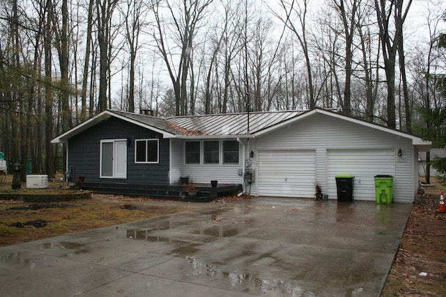 ranch-style house featuring an attached garage, a standing seam roof, and metal roof