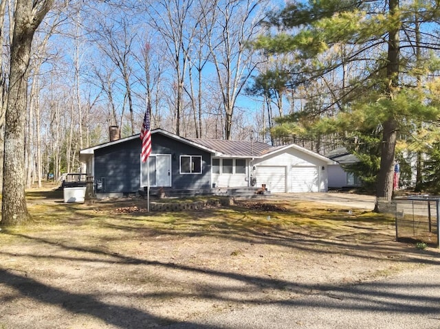 234 Pocahontas Ave, Roscommon, MI 48653 - ranch-style house featuring driveway, metal roof, a chimney, and a garage