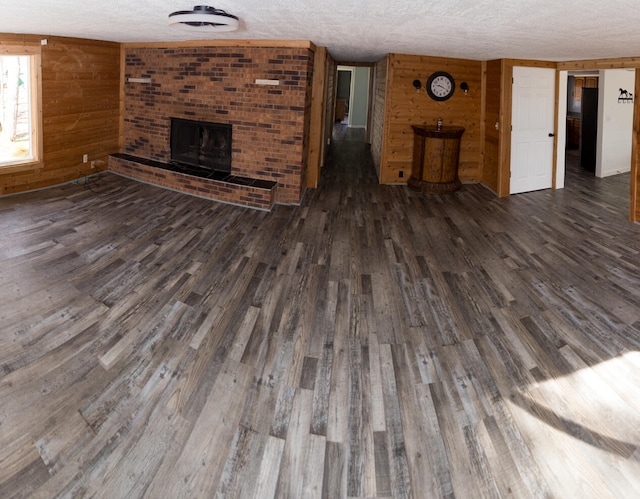 234 Pocahontas Ave, Roscommon, MI 48653 - unfurnished living room featuring wooden walls, a fireplace, a textured ceiling, and wood finished floors