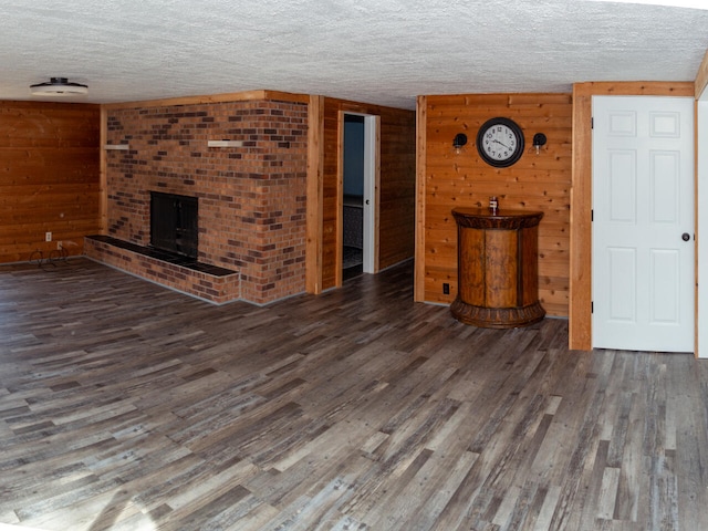 234 Pocahontas Ave, Roscommon, MI 48653 - unfurnished living room with a fireplace, wood walls, a textured ceiling, and wood finished floors