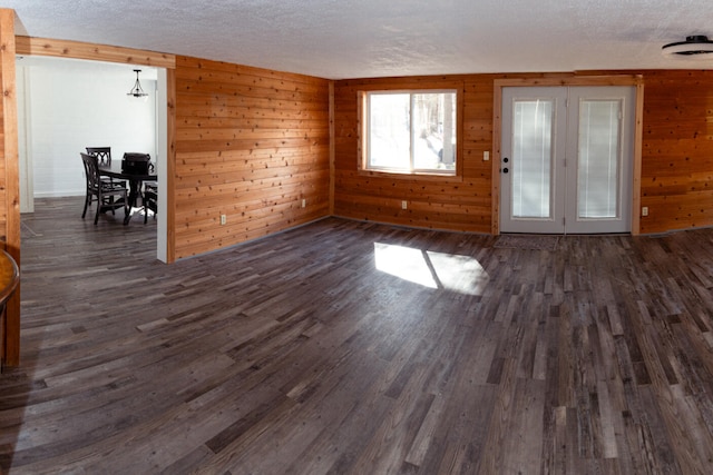 234 Pocahontas Ave, Roscommon, MI 48653 - unfurnished living room with wooden walls, a textured ceiling, and dark wood-type flooring