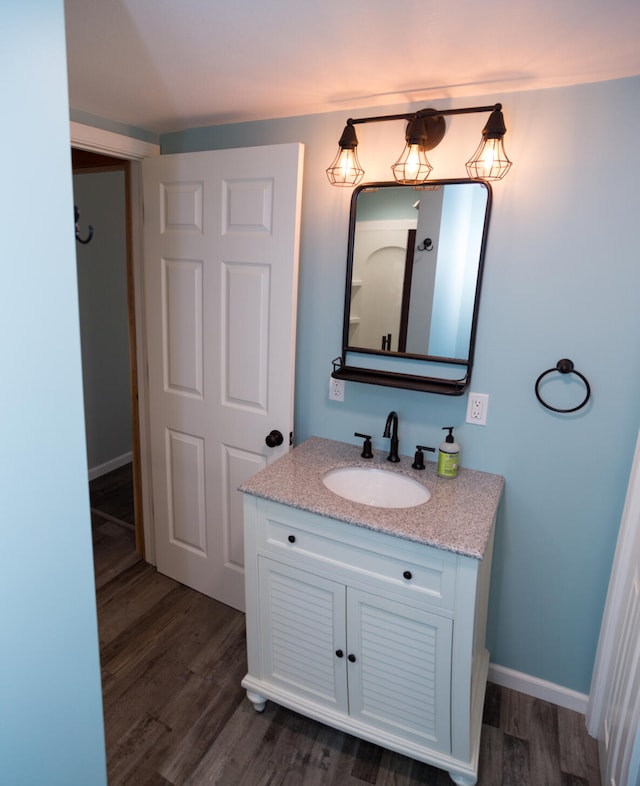 234 Pocahontas Ave, Roscommon, MI 48653 - bathroom featuring baseboards, vanity, and wood finished floors