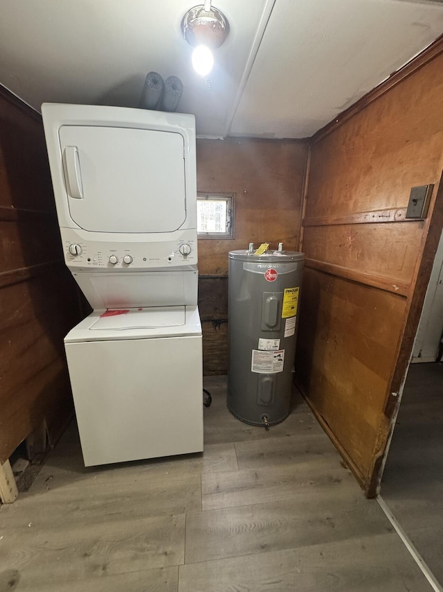 clothes washing area with wood finished floors, laundry area, stacked washer / dryer, and electric water heater