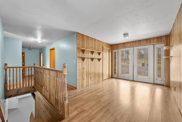 207 Cindy Ave, Roscommon, MI 48653 - unfurnished room featuring wood finished floors, wooden walls, baseboards, a textured ceiling, and french doors