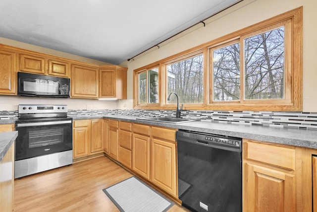 207 Cindy Ave, Roscommon, MI 48653 - kitchen with black appliances, a sink, light wood-style flooring, and backsplash