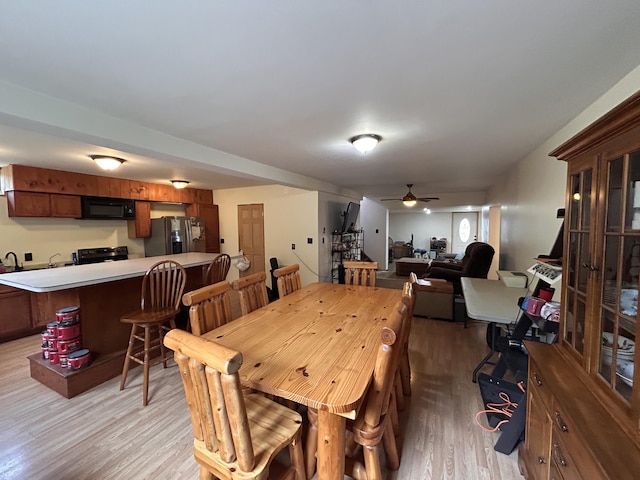 dining space with ceiling fan and light wood-style flooring
