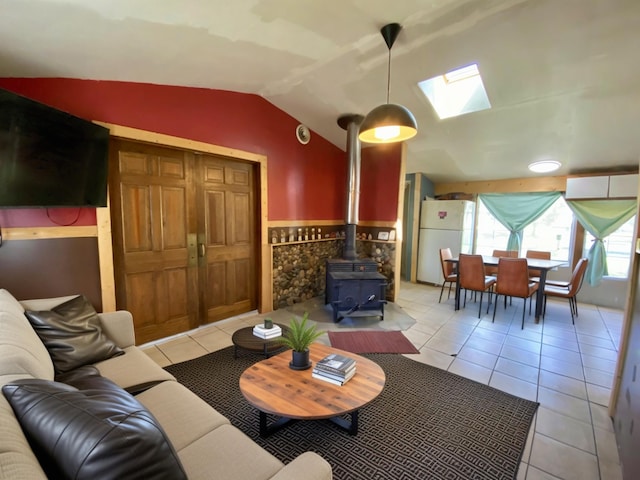 tiled living area with a wood stove and vaulted ceiling with skylight