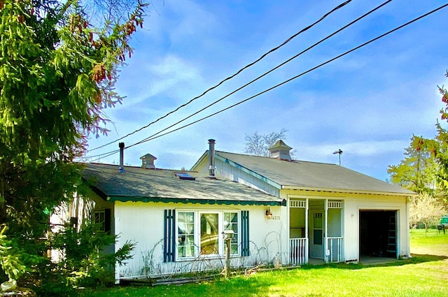 back of property with a lawn, covered porch, and an attached garage