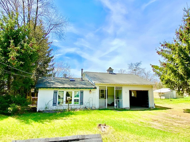 rear view of property featuring a garage and a yard