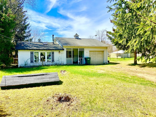 rear view of property with an attached garage, a lawn, and driveway