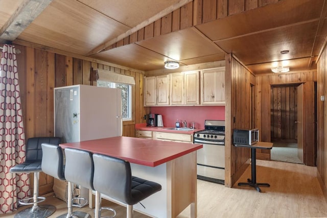 15757 Lakeway Dr, Wolverine, MI 49799 - kitchen with wood ceiling, gas stove, a sink, wooden walls, and light wood-style floors