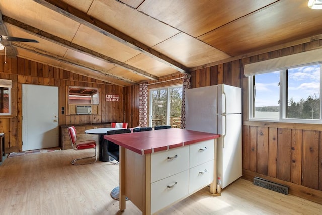 15757 Lakeway Dr, Wolverine, MI 49799 - kitchen with white cabinets, light wood finished floors, tile counters, wood walls, and vaulted ceiling with beams