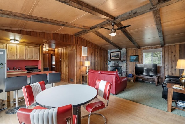 15757 Lakeway Dr, Wolverine, MI 49799 - dining room featuring wood walls, wood finished floors, a stone fireplace, vaulted ceiling with beams, and wood ceiling