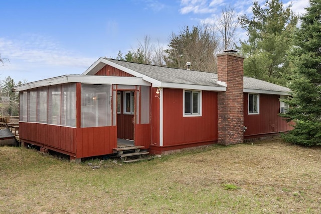 15757 Lakeway Dr, Wolverine, MI 49799 - rear view of house with a sunroom, roof with shingles, a yard, and a chimney