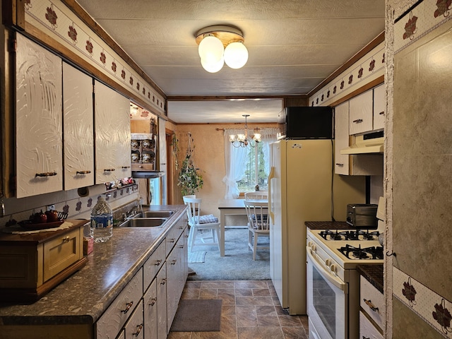 kitchen with a sink, gas range gas stove, stone finish floor, under cabinet range hood, and dark countertops