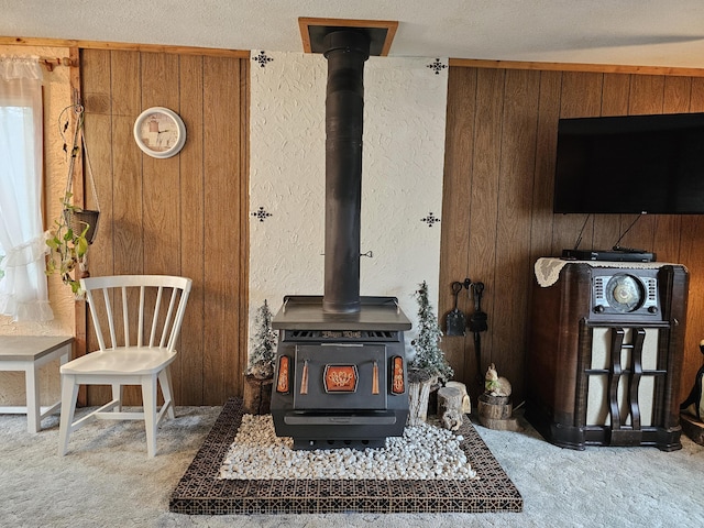 interior details featuring a wood stove, wooden walls, carpet floors, and a textured wall