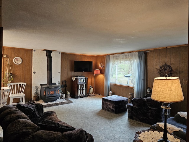 living area with a wood stove, wood walls, a textured ceiling, and carpet floors