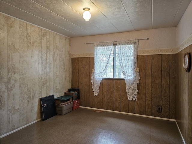 unfurnished room with tile patterned floors, wood walls, and visible vents