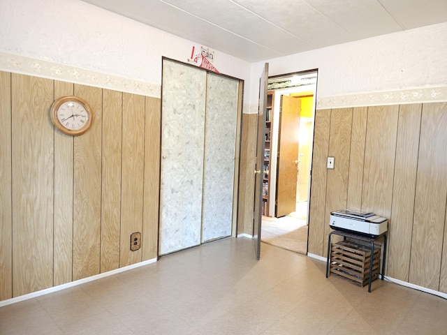 bedroom with tile patterned floors, wood walls, and a closet