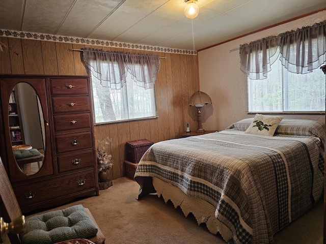bedroom with light colored carpet, multiple windows, and wooden walls