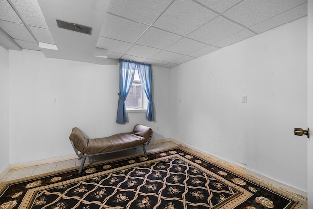 sitting room with baseboards, visible vents, and a drop ceiling