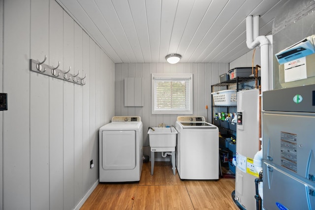 5012 Green Acre Dr, Frederic, MI 49733 - laundry room featuring washing machine and dryer, light wood-style floors, water heater, wood walls, and heating unit