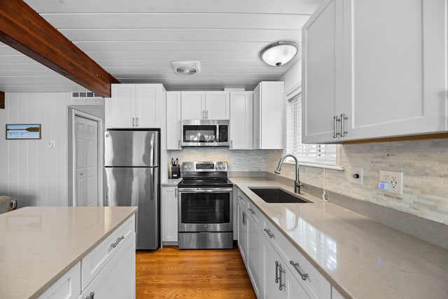 5012 Green Acre Dr, Frederic, MI 49733 - kitchen with appliances with stainless steel finishes, a sink, tasteful backsplash, white cabinetry, and beam ceiling