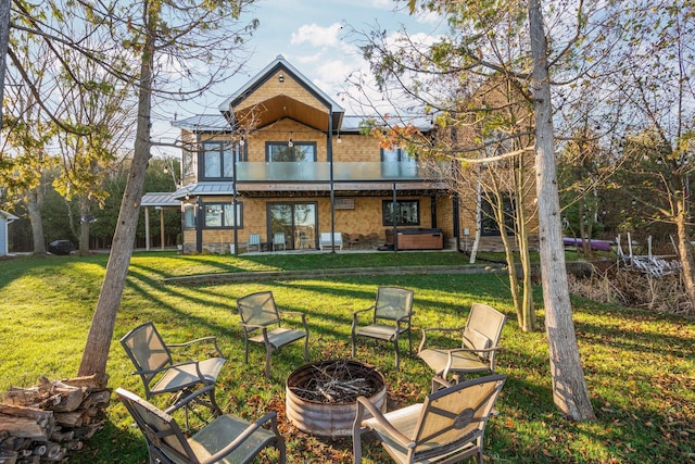 835 M-88, Bellaire, MI 49615 - back of property with a hot tub, a fire pit, a lawn, and a standing seam roof